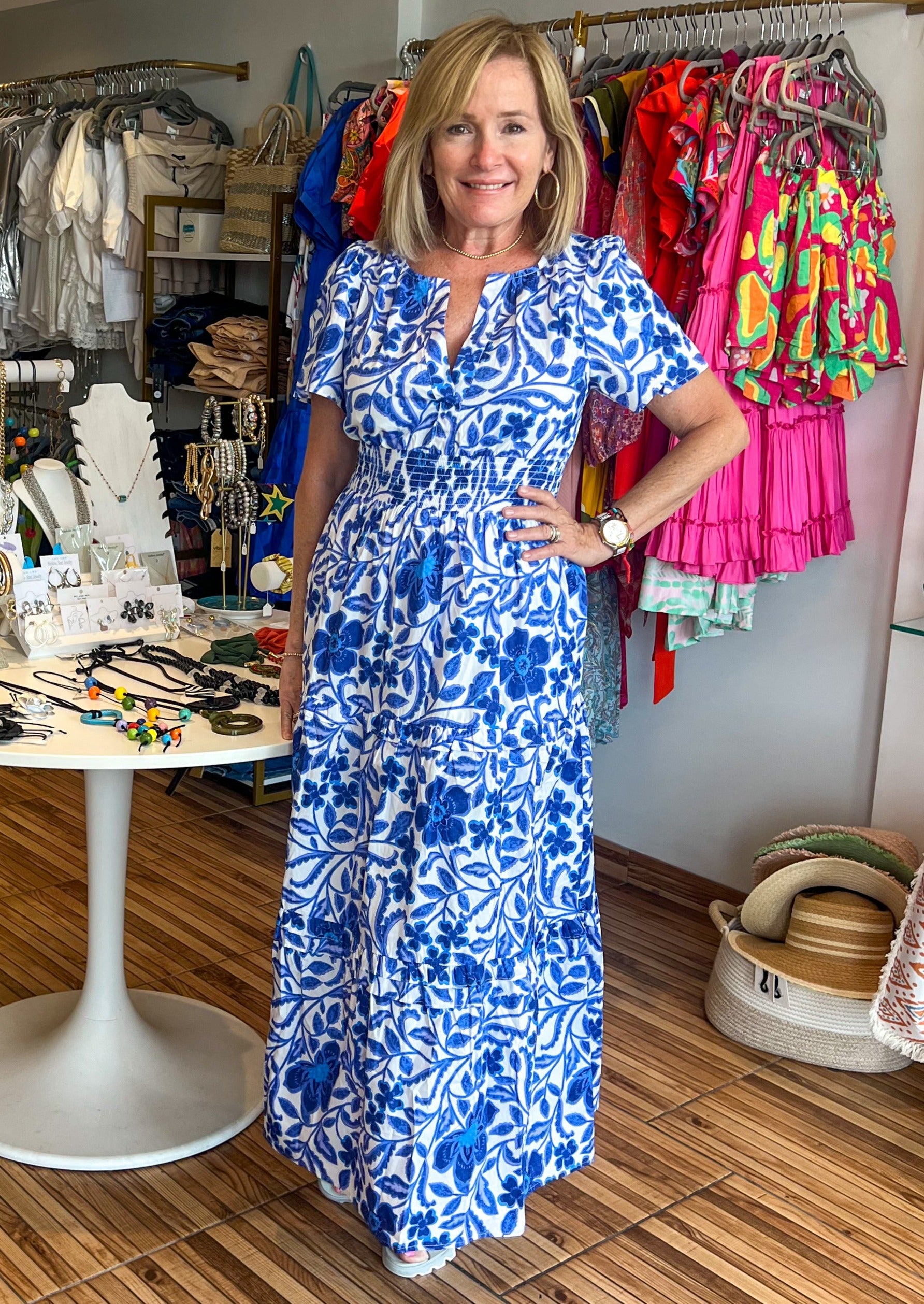 Celeste Floral Palmer Poplin Tiered Maxi Dress! It features billowed short sleeves that frame a split neckline where it meets a smocked waistline. Side pockets sit at the seam of a ruffle tiered midi skirt.