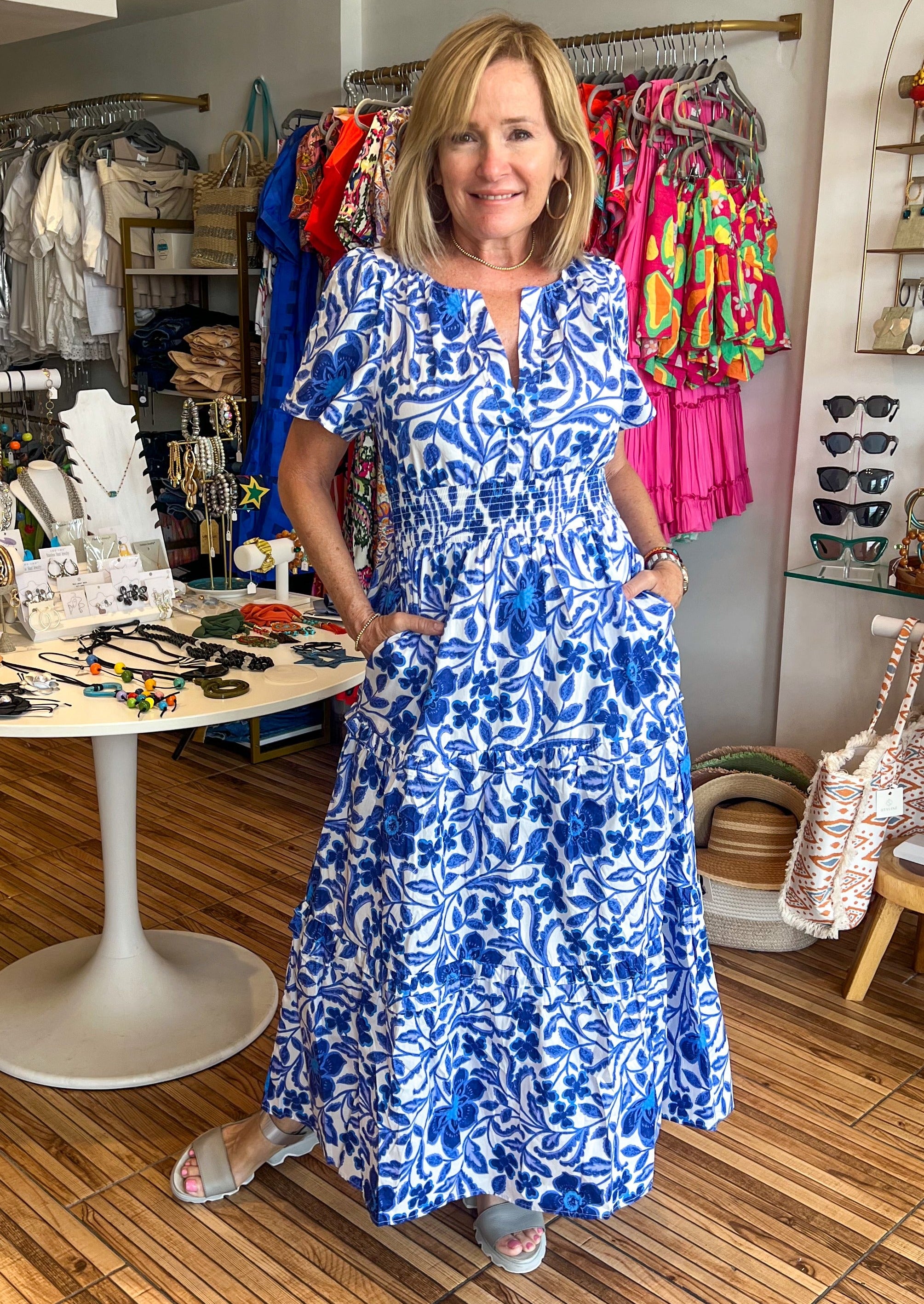 Celeste Floral Palmer Poplin Tiered Maxi Dress! It features billowed short sleeves that frame a split neckline where it meets a smocked waistline. Side pockets sit at the seam of a ruffle tiered midi skirt.