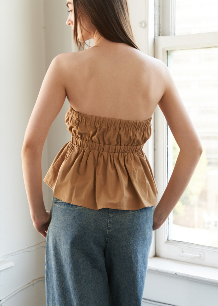 Camel solid woven top featuring strapless, button down, elasticized waist, button down detail and peplum.