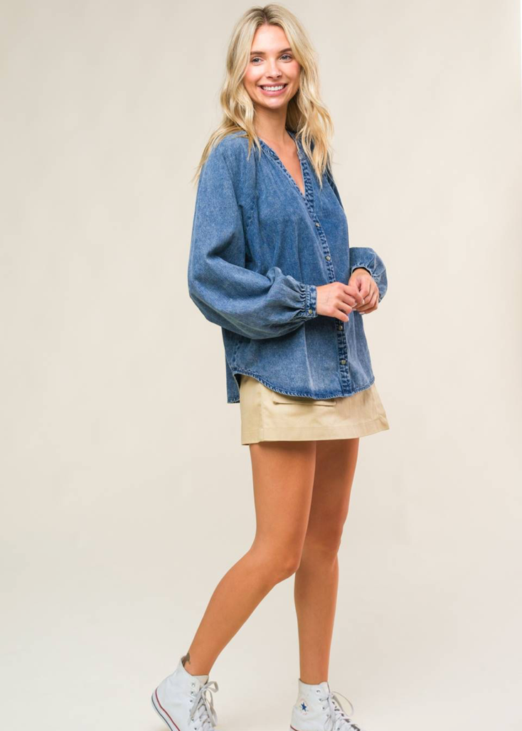 An acid washed denim top with round neckline, long raglan sleeve and button down