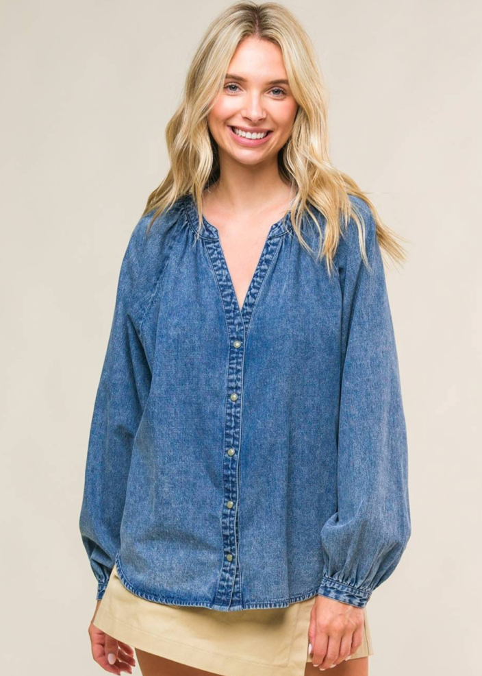 An acid washed denim top with round neckline, long raglan sleeve and button down