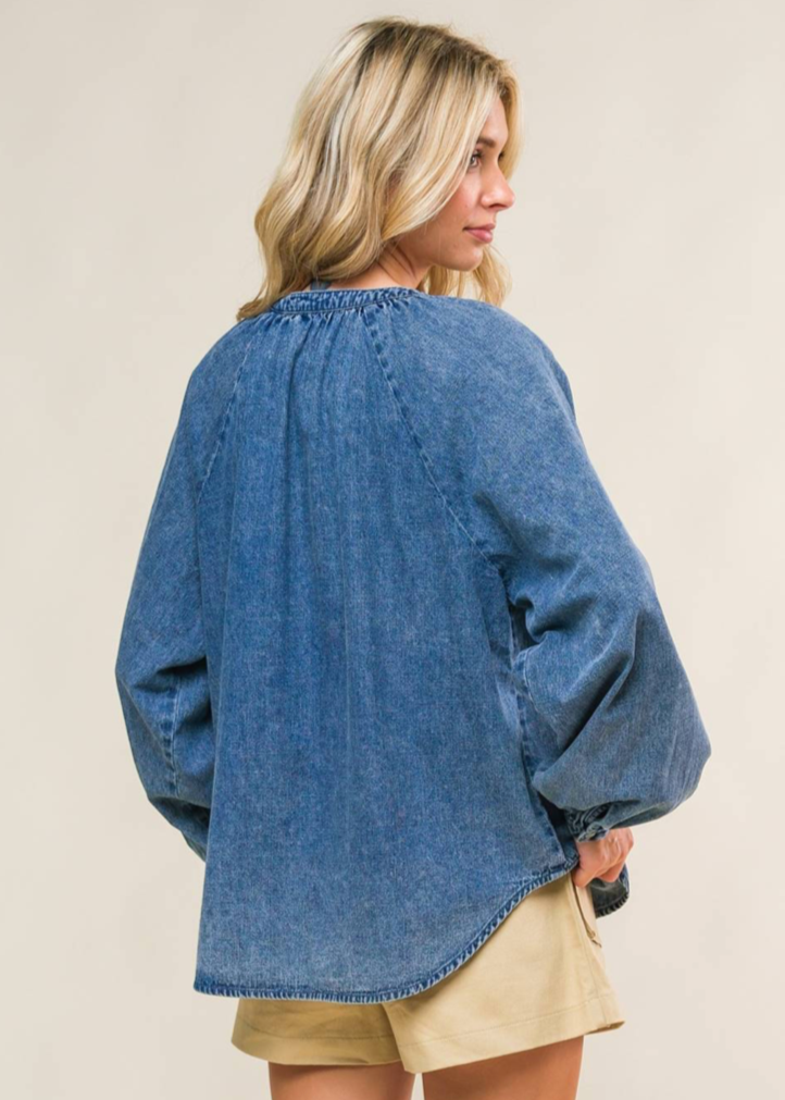 An acid washed denim top with round neckline, long raglan sleeve and button down